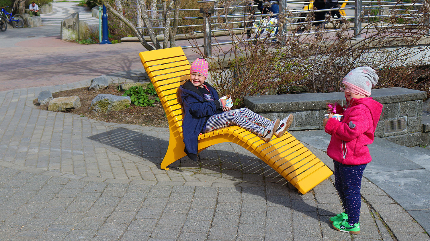 Little girl eating ice cream sitting on yellow chaise lounge