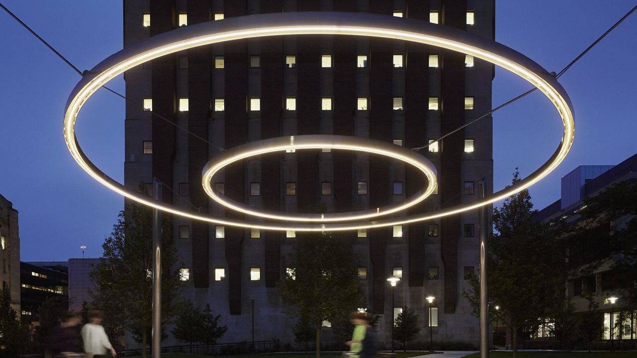 Circle of light suspended in sky with building behind