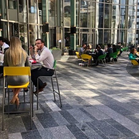 People gathered outside at Plaza sitting in yellow and green chairs