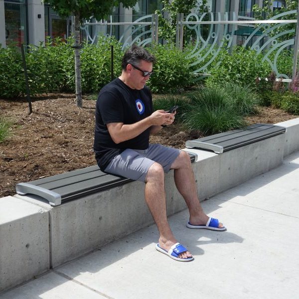 Man sitting on backless bench on phone