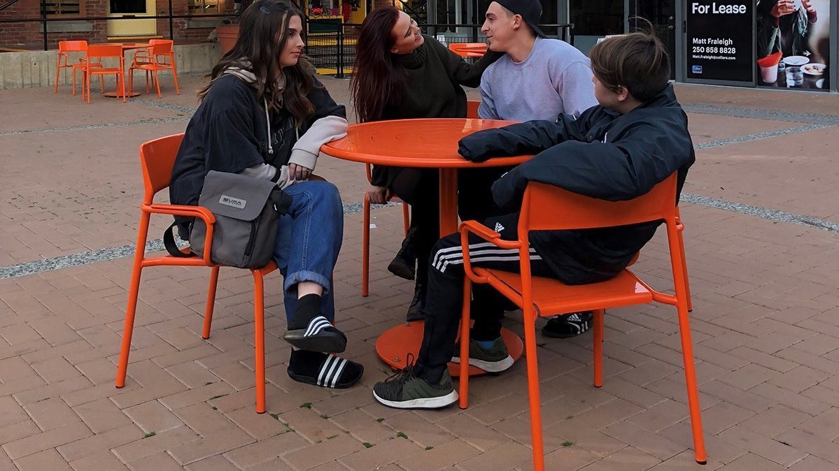 Friends sitting at Orange Table and Chairs at Market