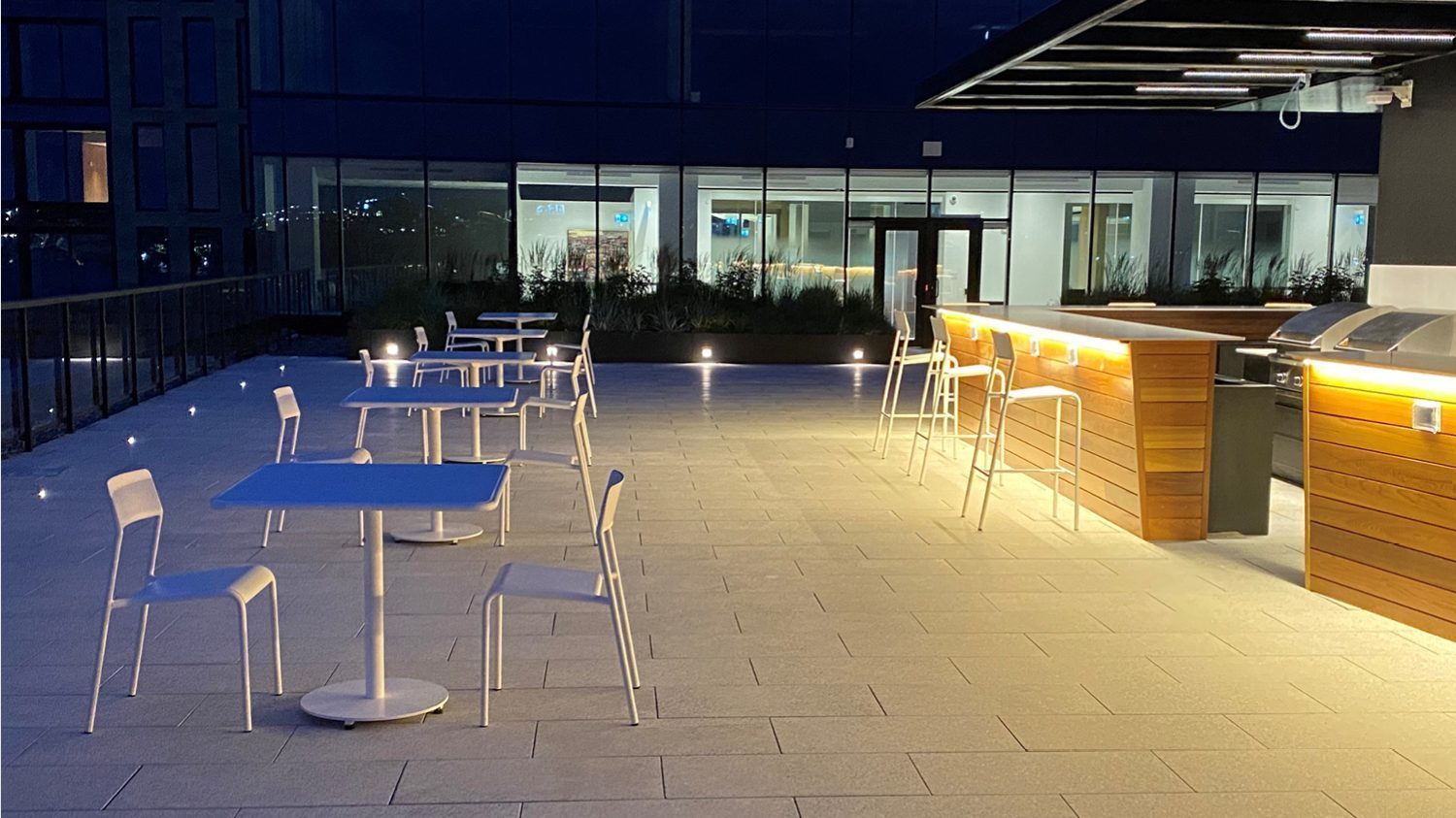 Night shot of Foro tables and chairs on roof top patio