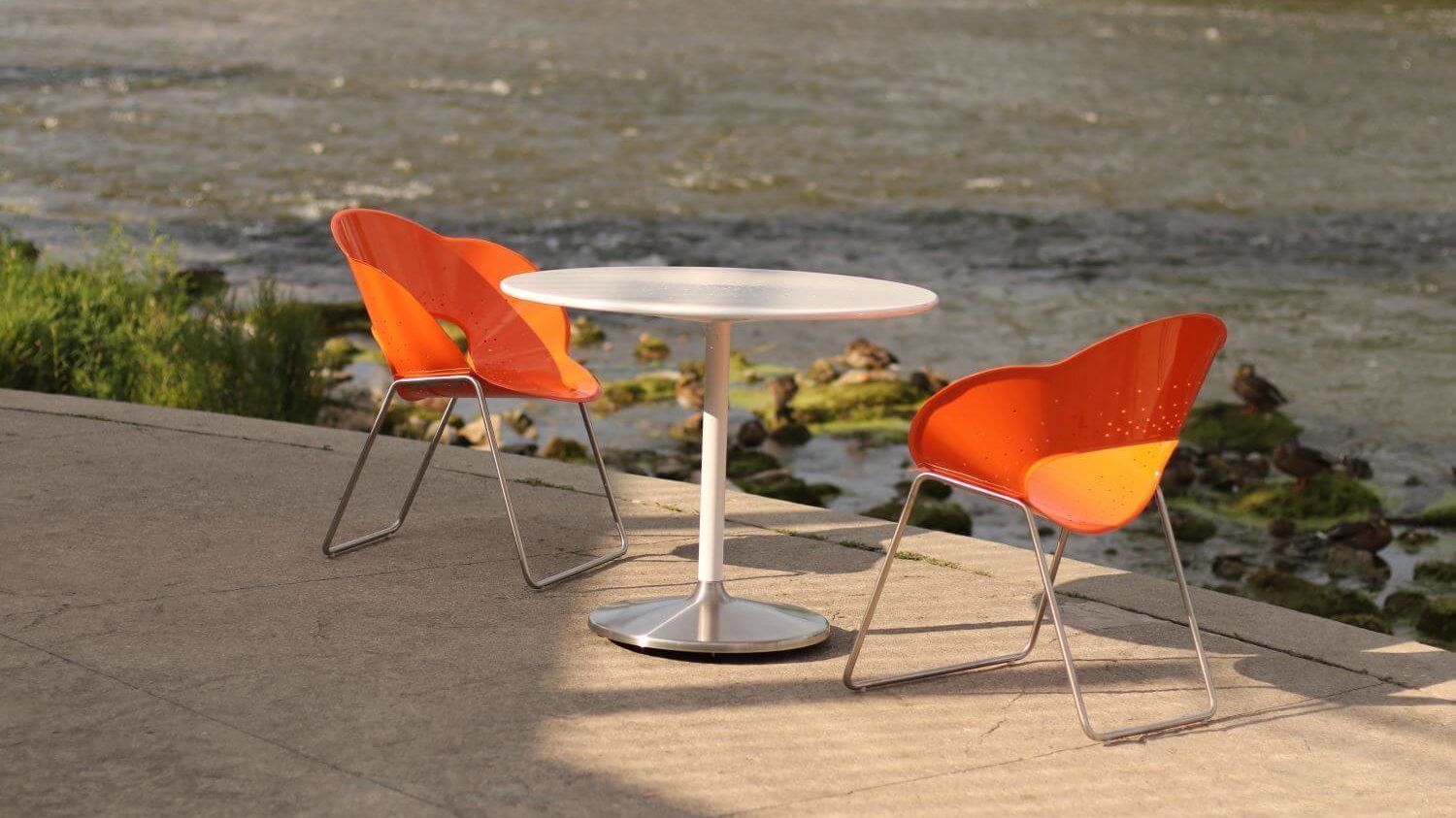 Orange chair with a white circular table overlooking a river