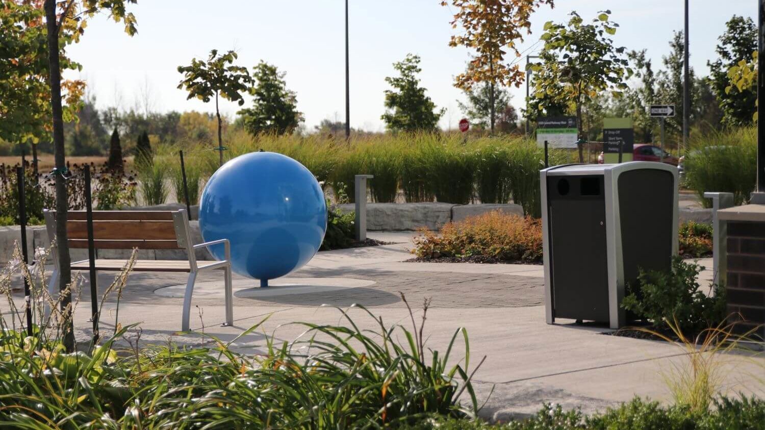 Trash bin near gardens and bench