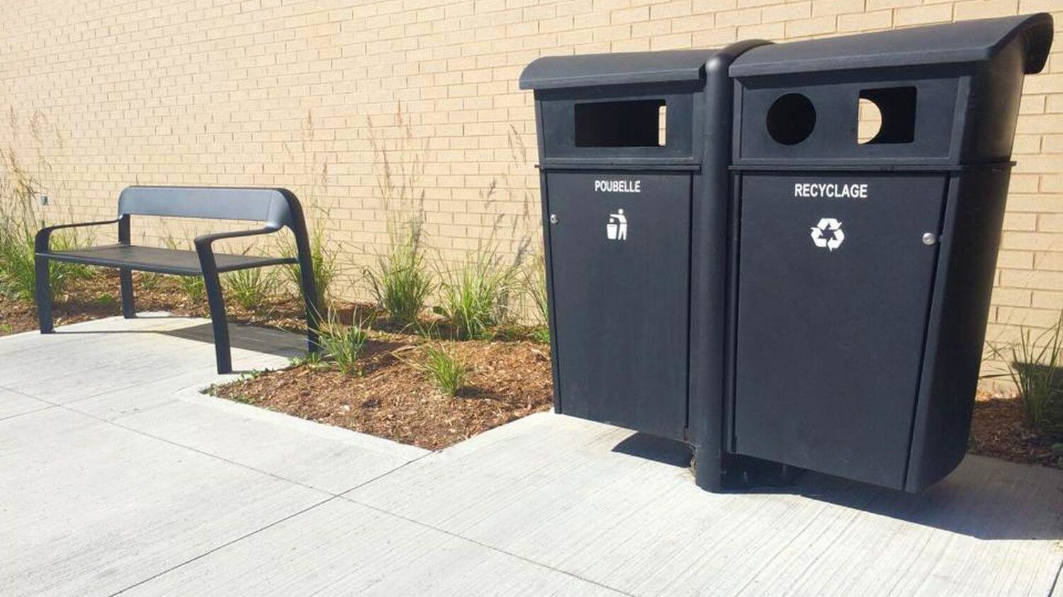 Two black bins next to a black bench