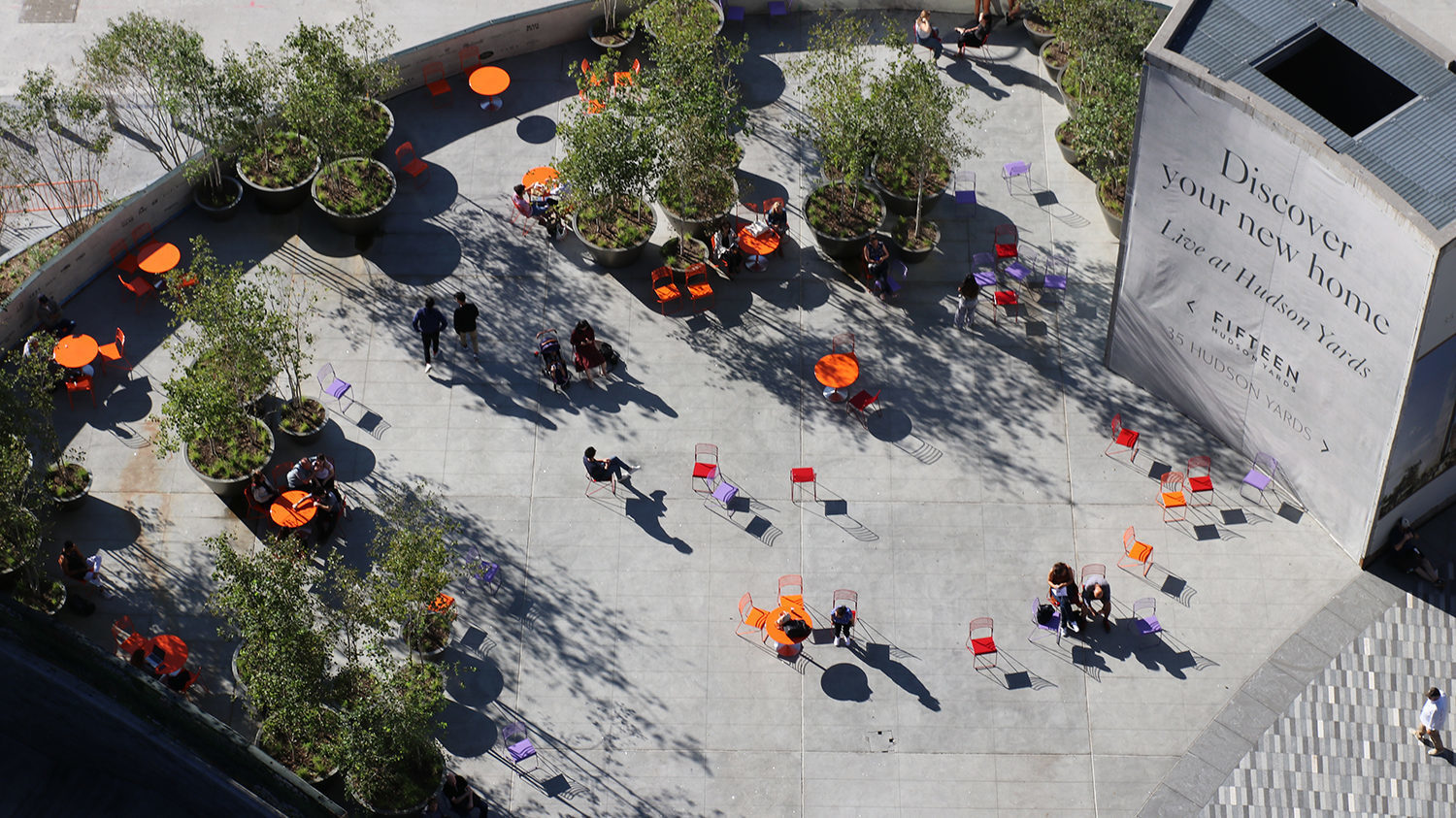 Looking down at Hudson Yards from the Vessel at brightly colored tables and chairs