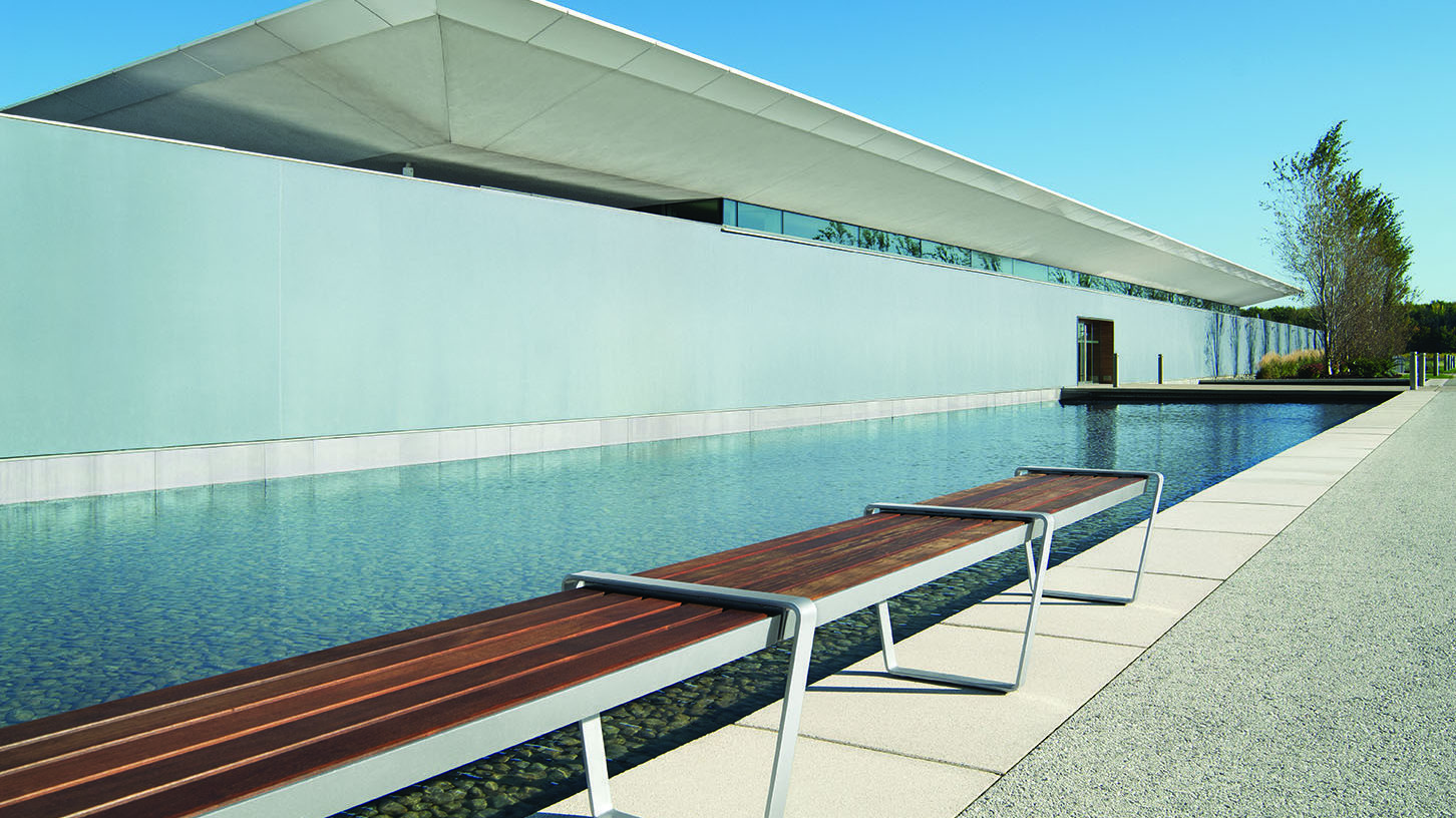 Straight wood Lexicon bench next to a modern building and a pool