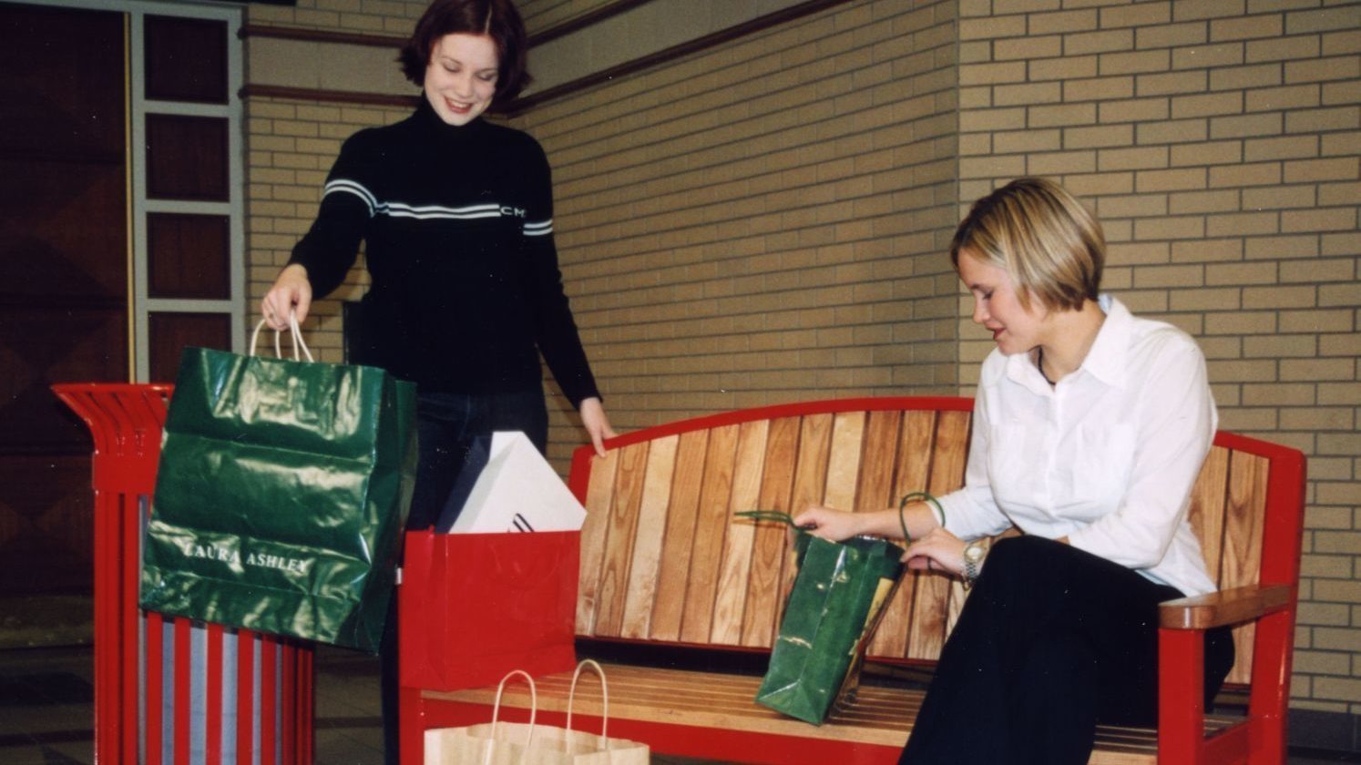 Maggie and Lindsay with shopping bags on a bench