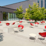 Red Battery Lounge Chairs beside White Tables Outside of Building