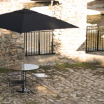 Three Metal Chairs with Round Table with an Attached Black Umbrella