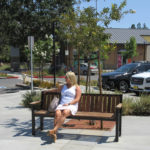 Woman in white sitting on backed bench