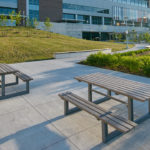 Grey Picnic Tables on Concrete Pads Outside of Building