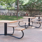 Multiple Tables with Individual Backless Seats outside near a Bike Rack