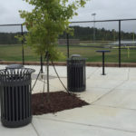 Two Trash Cans Outside a Sports Field