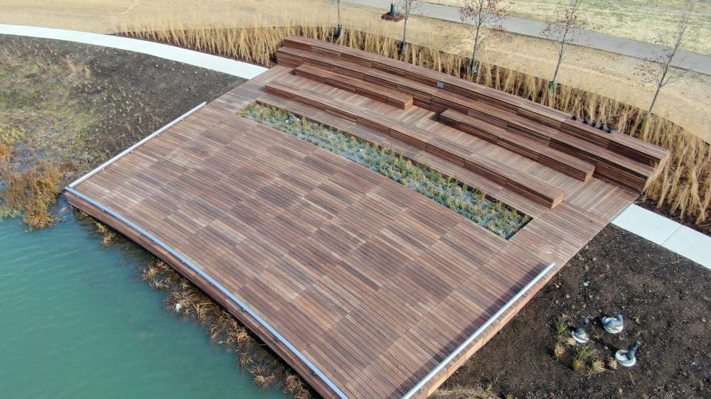 Custom Amphitheater, wooden stage next to water and greenery