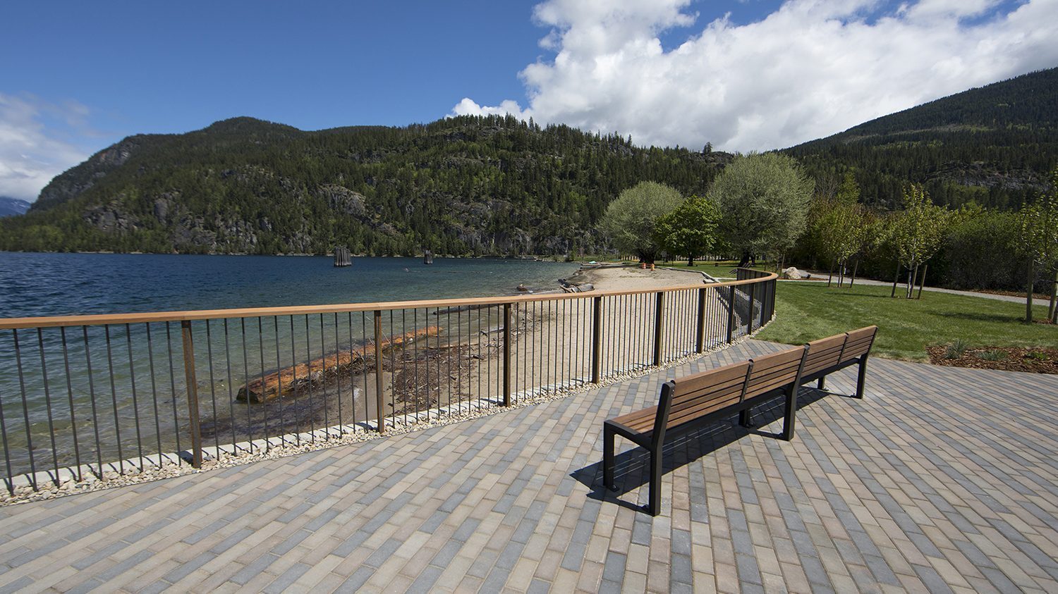 Two wood benches overlook mountains and a lake