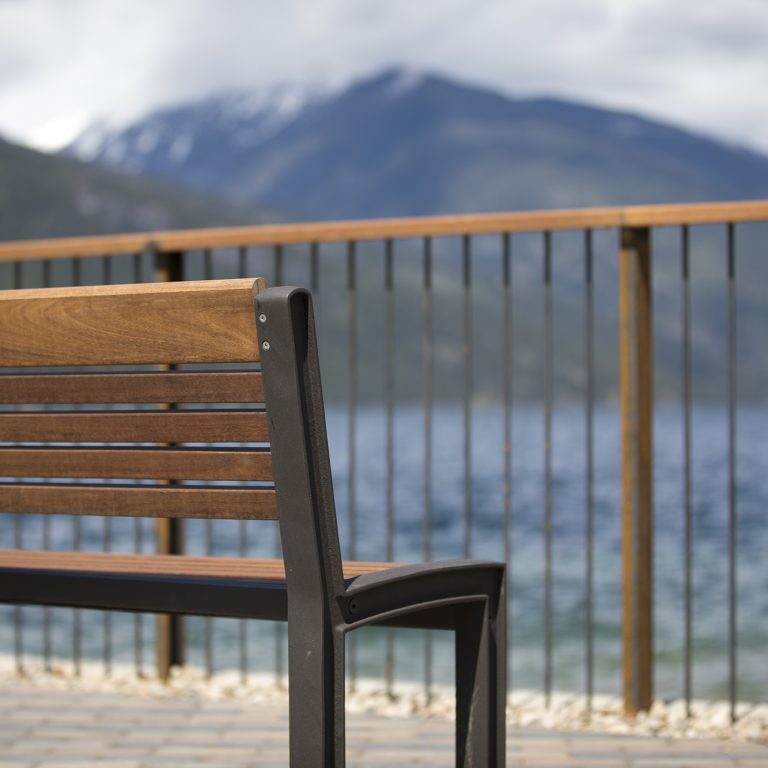 Closeup of the back of a wooden bench in the foreground, blurry mountains beyond