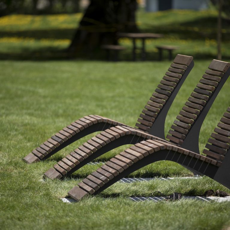 Three wooden lounge side-by-side on grass