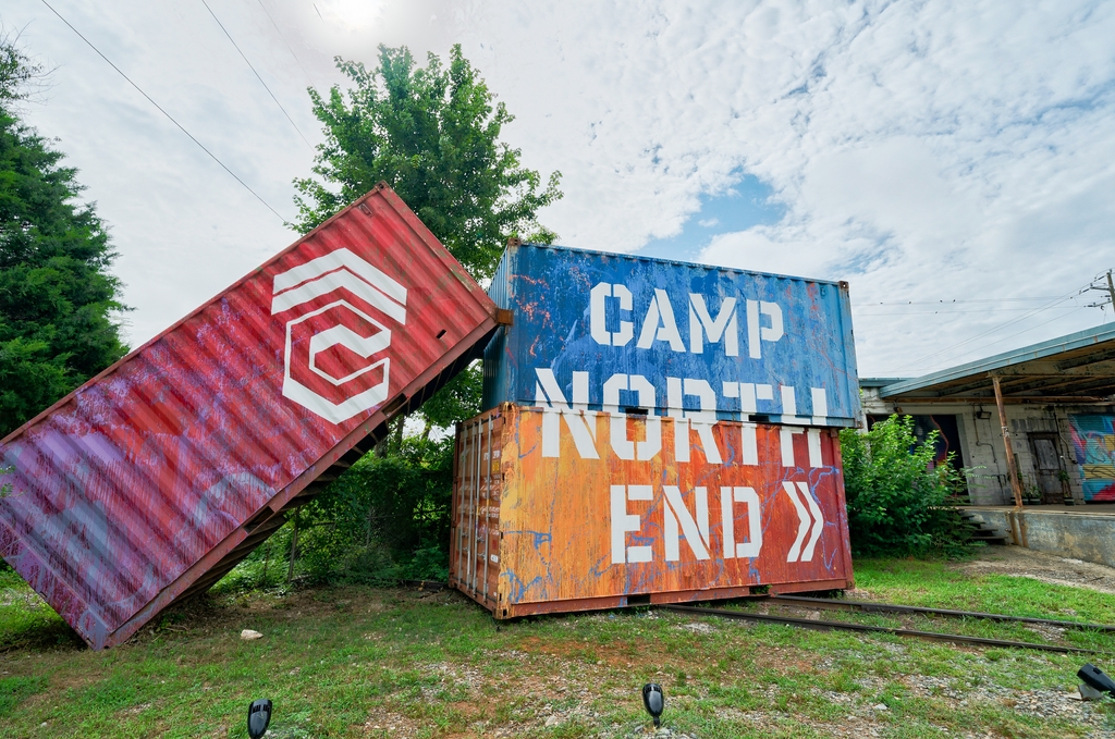 Three stacked shipping containers are painted to read CAMP NORTH END