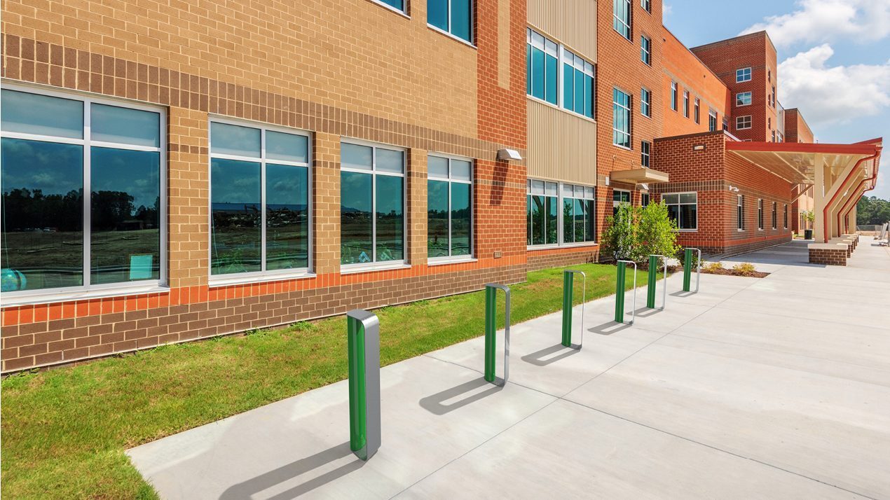 MUG Bike Racks painted gloss green and gunmetal in front of school  building