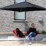 Jill Roberts sitting on battery chairs being shaded by a Tuuci Umbrella