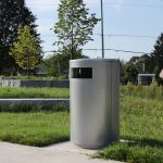 MTR-0650-00011: 650 Metal Trash Receptacle painted Silver 14 surrounded by greenery