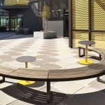 Curved Ogden Bench with two steel Ogden tables in courtyard