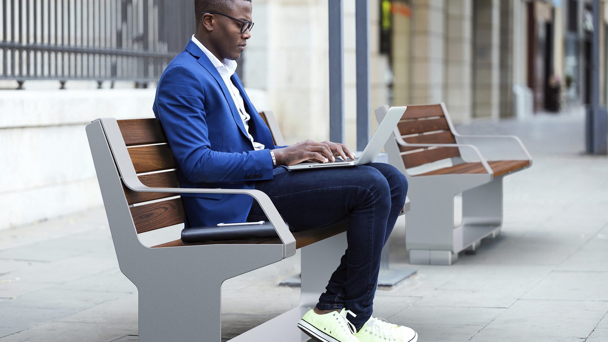 Man sitting on L-Series Backed Bench on city street