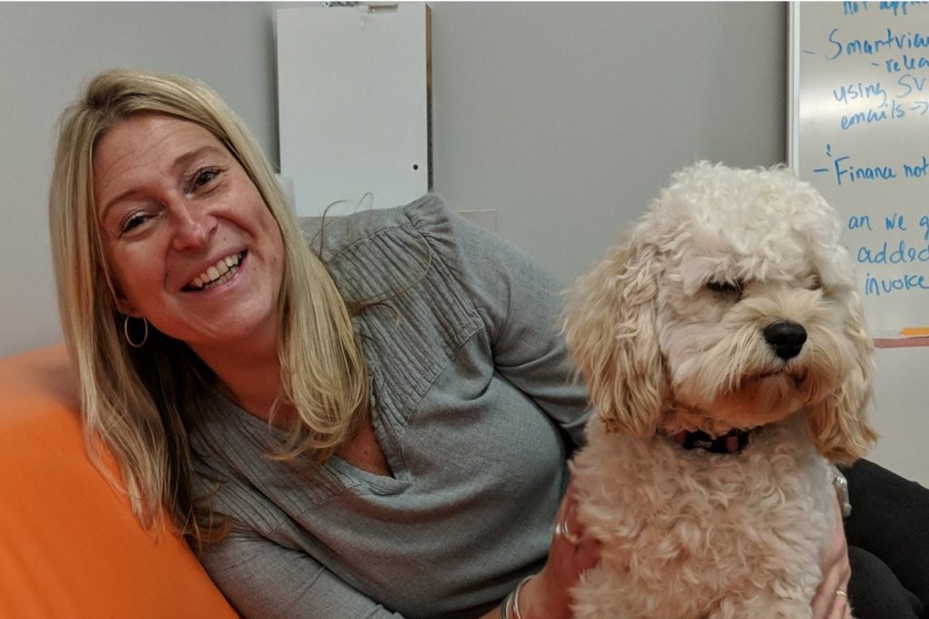 Jill smiling with a cute puppy at work