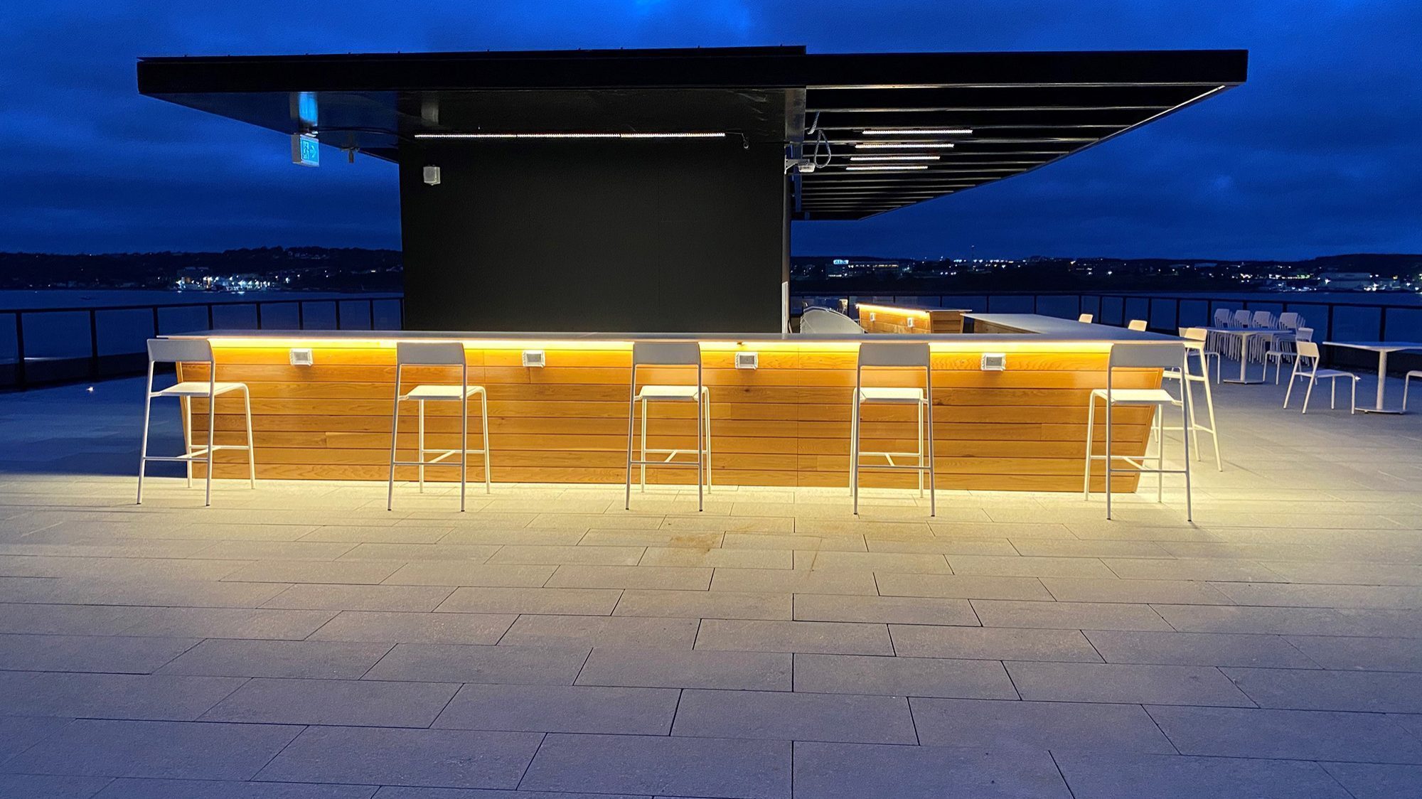 White Foro stools are lined up next to the bar on the rooftop terrace of Stewart McKelvey