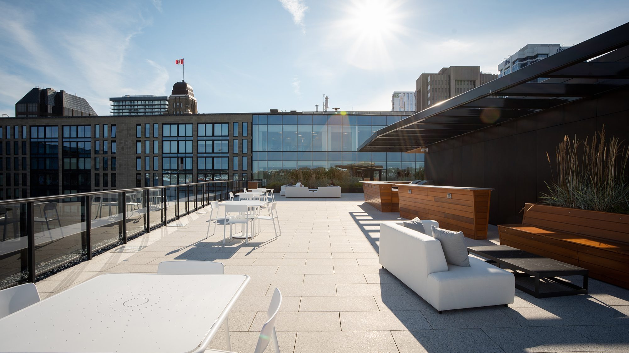 White Foro tables and chairs on the rooftop terrace of Stewart McKelvey. Office buildings are in the background.