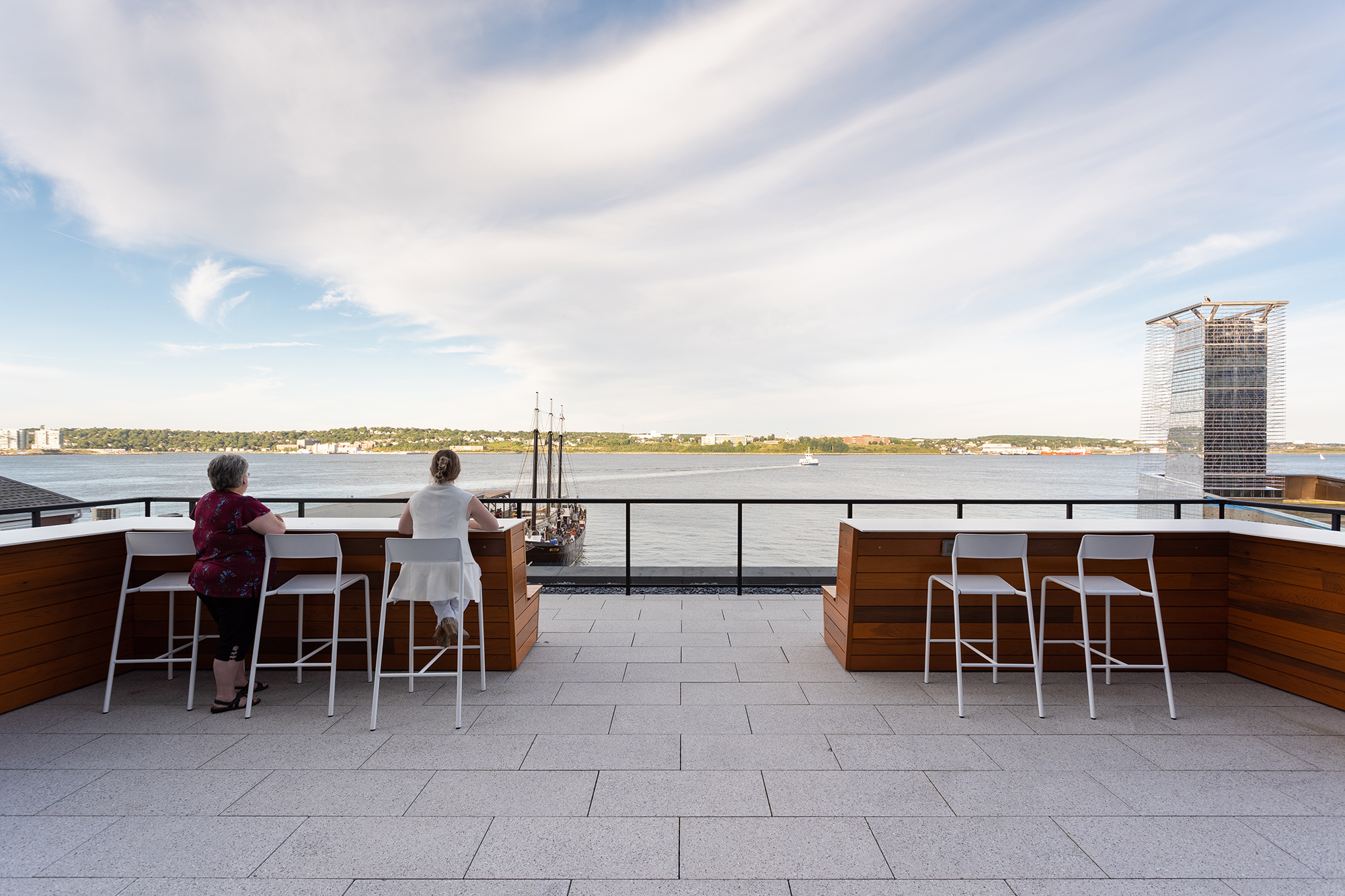 Two employees look out on the harbor from Foro stools on the Stewart McKelvey rooftop terrace