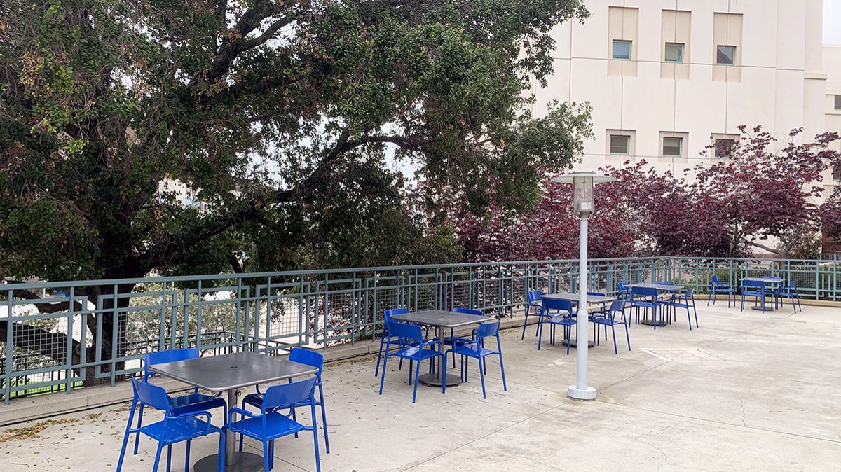 Five square Maglin Foro Tables each surrounded by blue Foro chairs on a patio at California State University San Marcos.