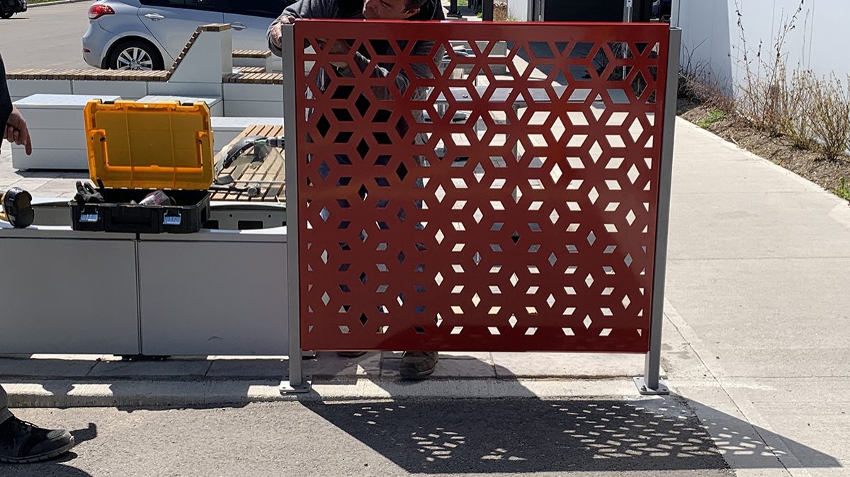 A man attaches a Maglin FLEXX panel to its bracket outside on a concrete surface.