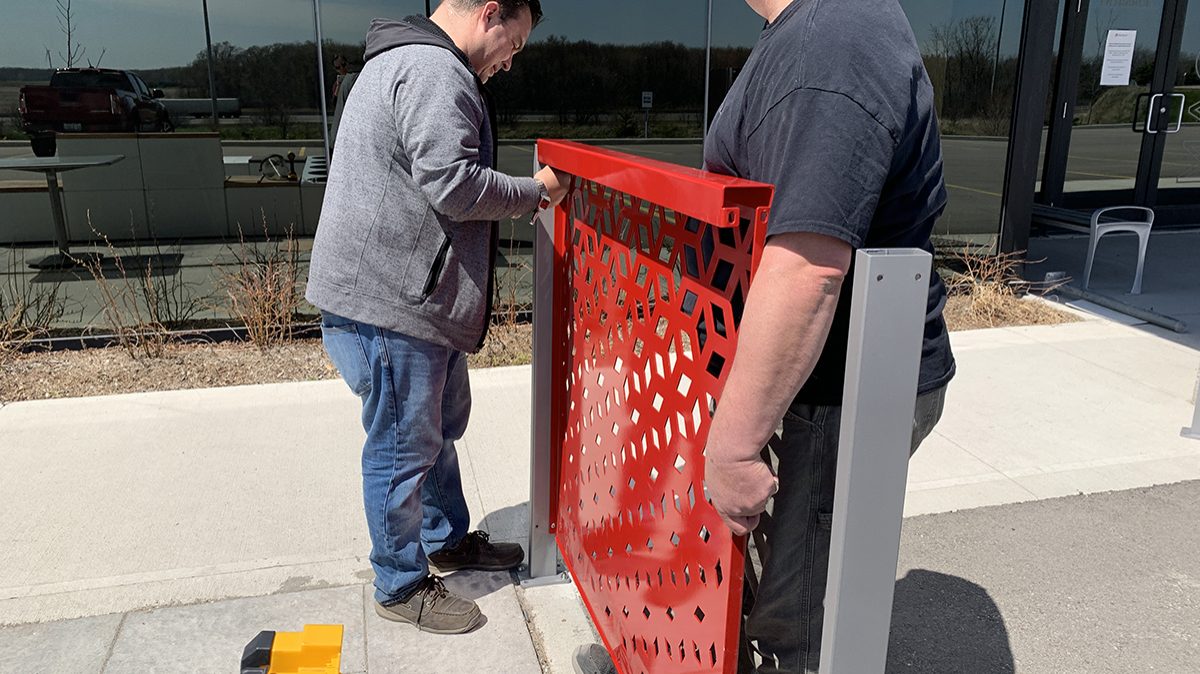 Two men work together to install a Maglin FLEXX panel on a concrete surface.