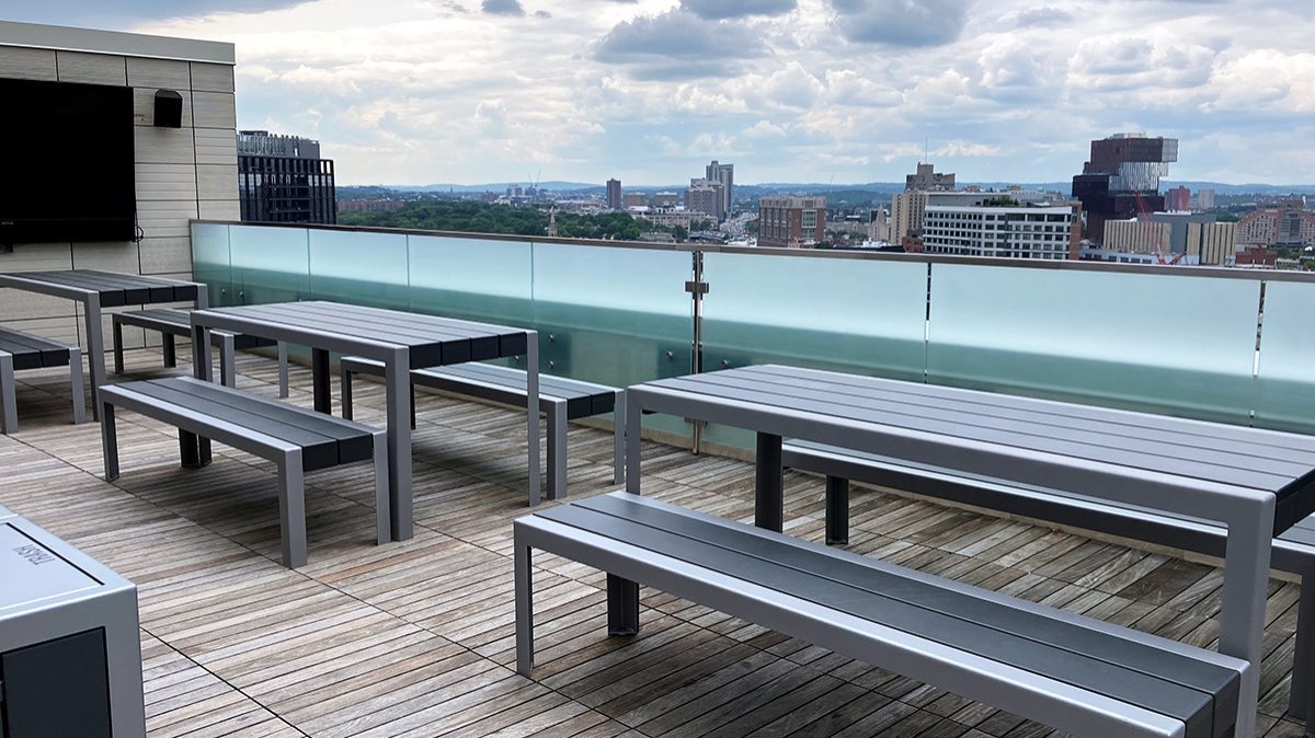 Three sets of 1050 tables and benches are lined up on the roof deck of Viridian Apartments.