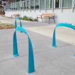 MBR-1600 SC Bike Racks, Surface Mount, Turquoise Gloss Powdercoat with retirement residence in background