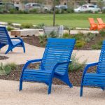 720 Chairs in gloss blue with orange chairs in the background in a park plaza