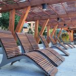 720 Chair Lounge in Ipe Wood under wooden pergola surrounded by trees and bushes