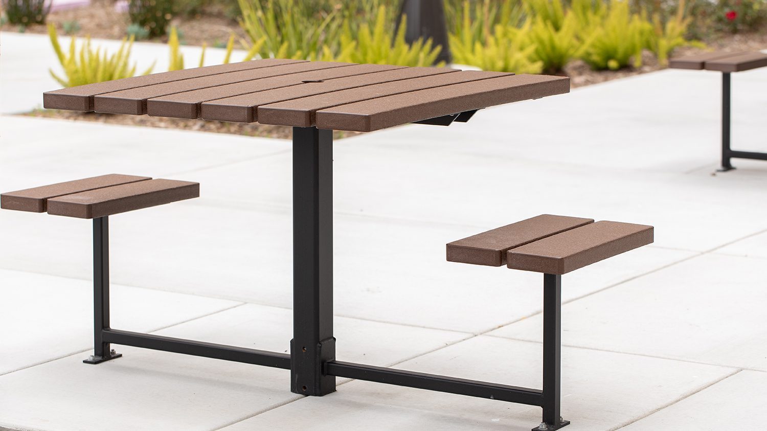 Maglin two-seat 400 Series cluster seating unit is installed on concrete in an apartment amenity courtyard in Chula Vista, CA. The table is open on either side to allow mobility and wheeled accessible devices to engage with the table.