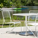 Powdercoated white Kontur Chairs with Battery Table on concrete pad next to lake