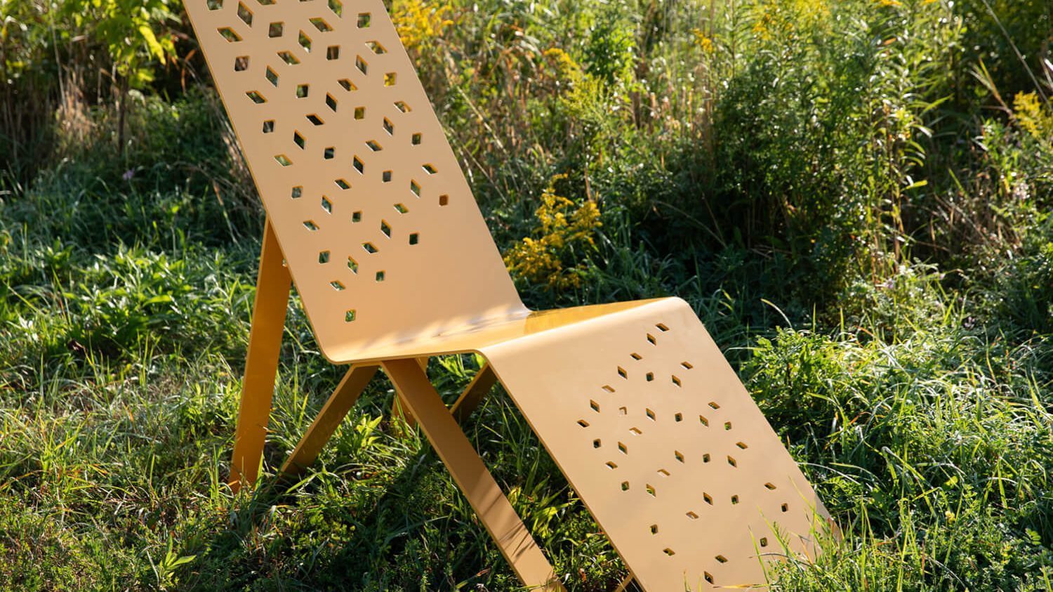 Saffron Yellow Maglin Chaise Lounge sitting amongst the greenery