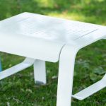 ALUM footrest/side table with Prosecco pattern in powdercoat white paint against greenery