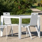 ALUM dining table with chairs powdercoated white with Fusion pattern on pathway with greenery in background