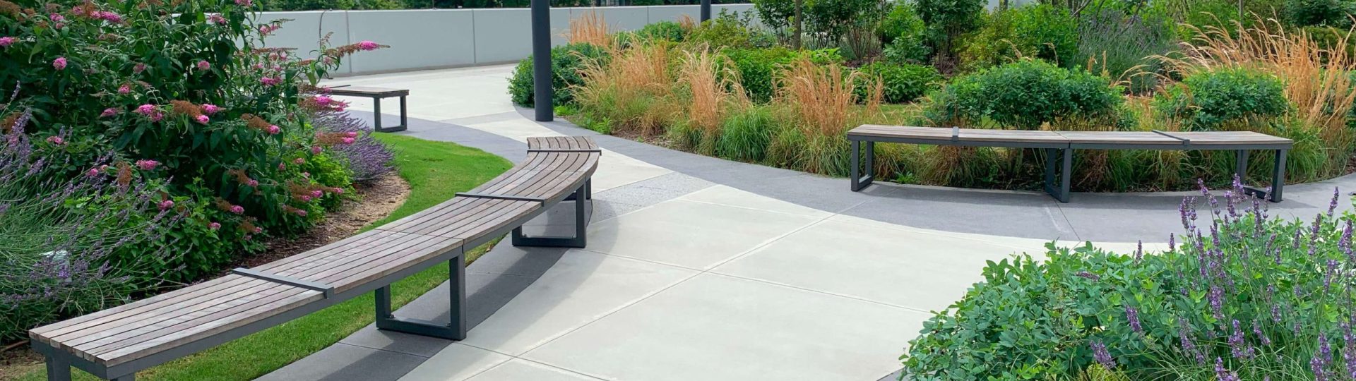 Backless Ogden benches sitting along pathway surrounded by greenery